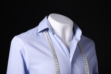 Photo of Male mannequin with light blue shirt and measuring tape on black background, closeup