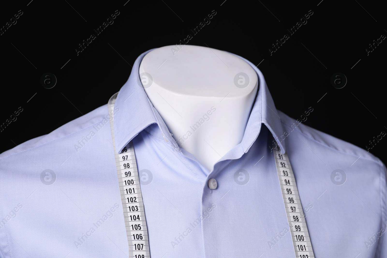 Photo of Male mannequin with light blue shirt and measuring tape on black background, closeup