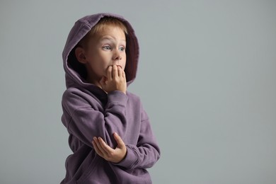 Photo of Scared little boy on grey background. Space for text