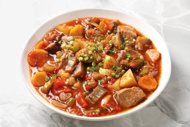 Photo of Delicious stew with vegetables in bowl on white marble table, closeup