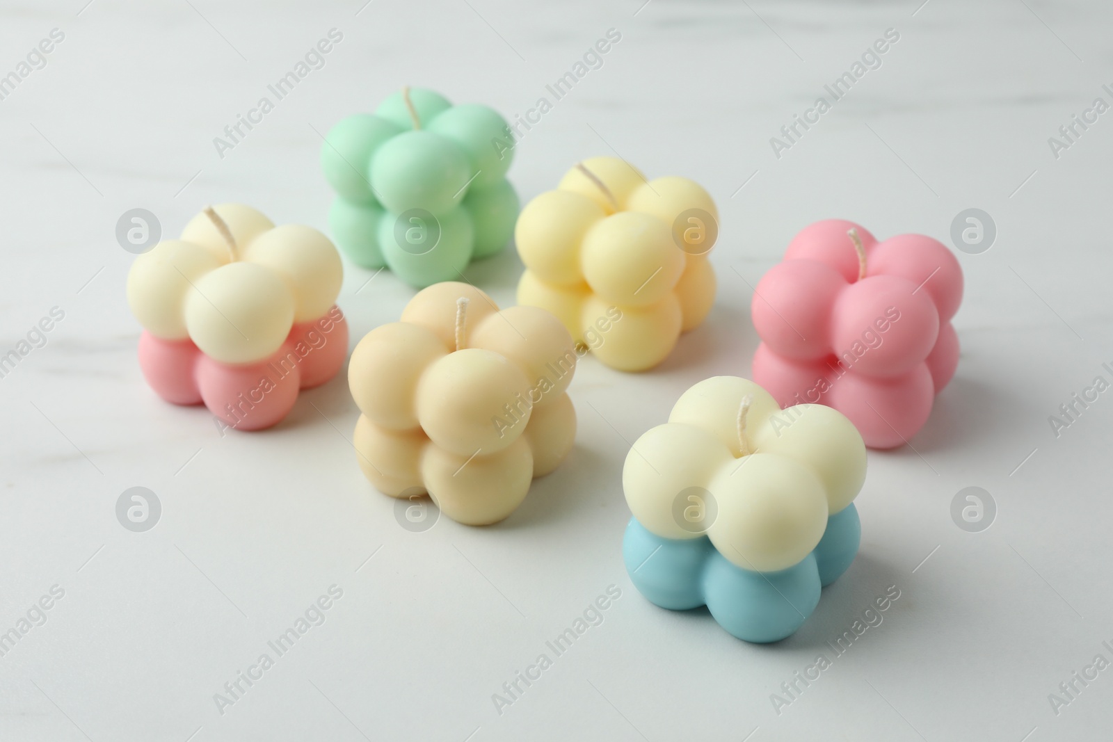 Photo of Different stylish bubble candles on white marble table, closeup