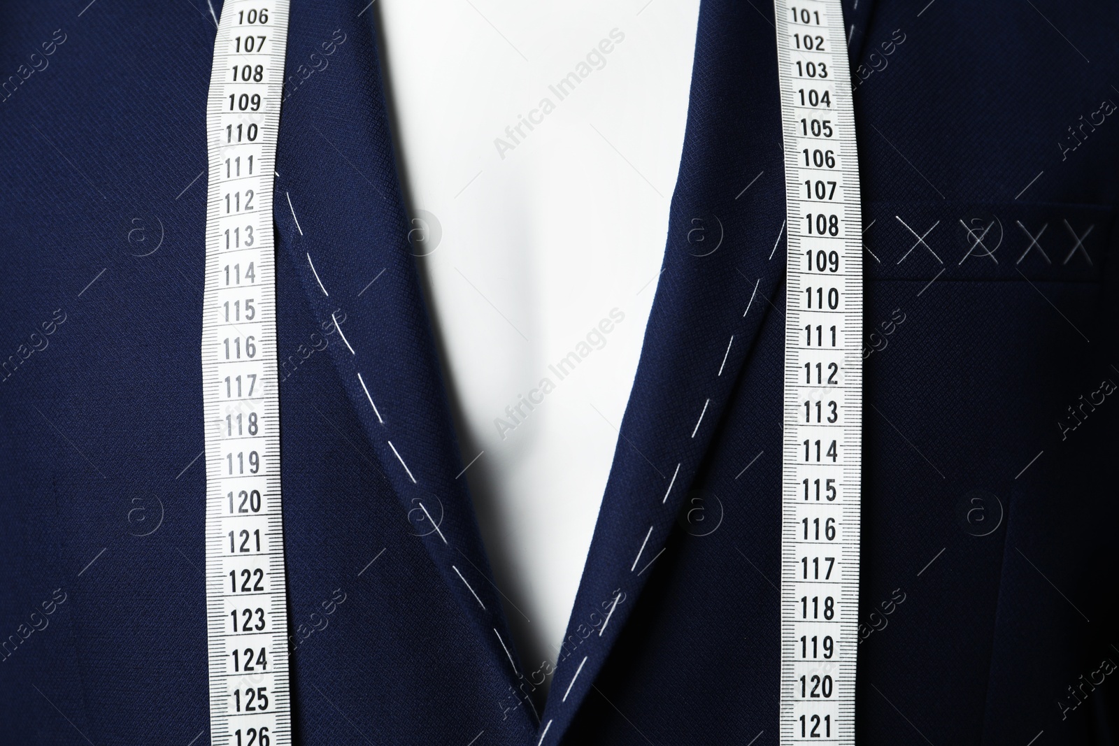 Photo of Semi-ready jacket with tailor's measuring tape on mannequin, closeup