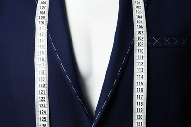 Photo of Semi-ready jacket with tailor's measuring tape on mannequin, closeup