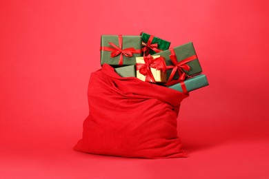 Photo of Santa Claus bag with gift boxes on red background