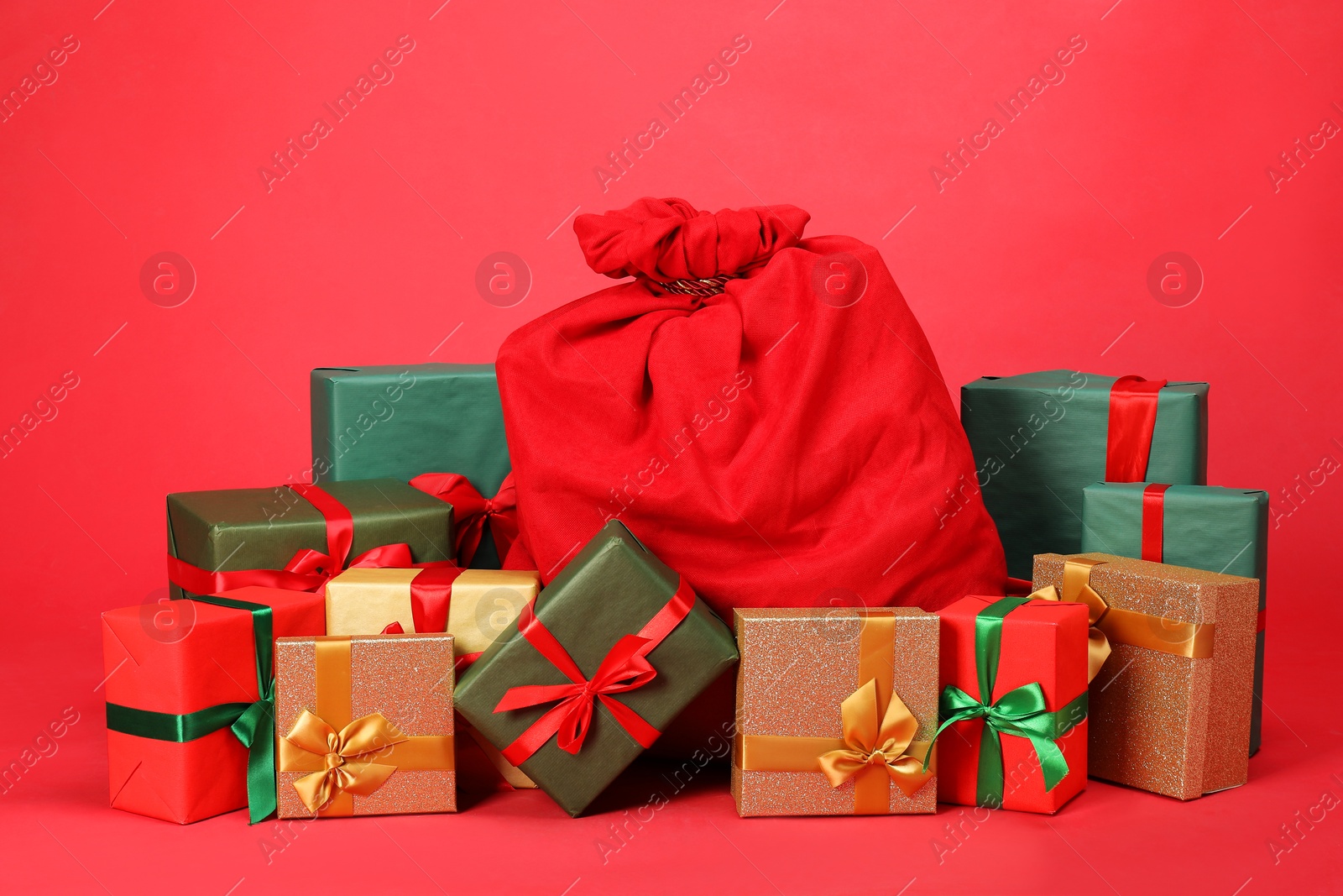 Photo of Santa Claus bag with gift boxes on red background