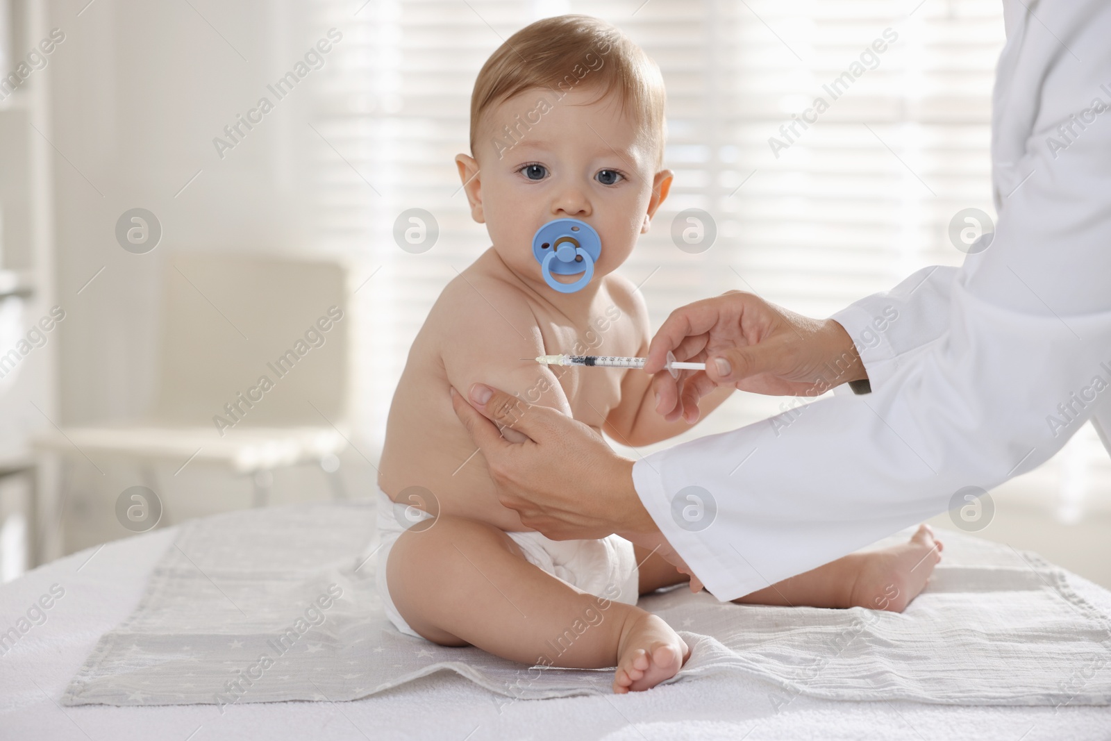 Photo of Pediatrician giving injection to cute baby in clinic, closeup