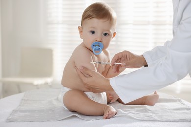 Photo of Pediatrician giving injection to cute baby in clinic, closeup