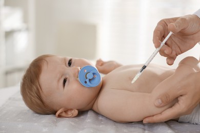 Photo of Pediatrician giving injection to cute baby in clinic, closeup