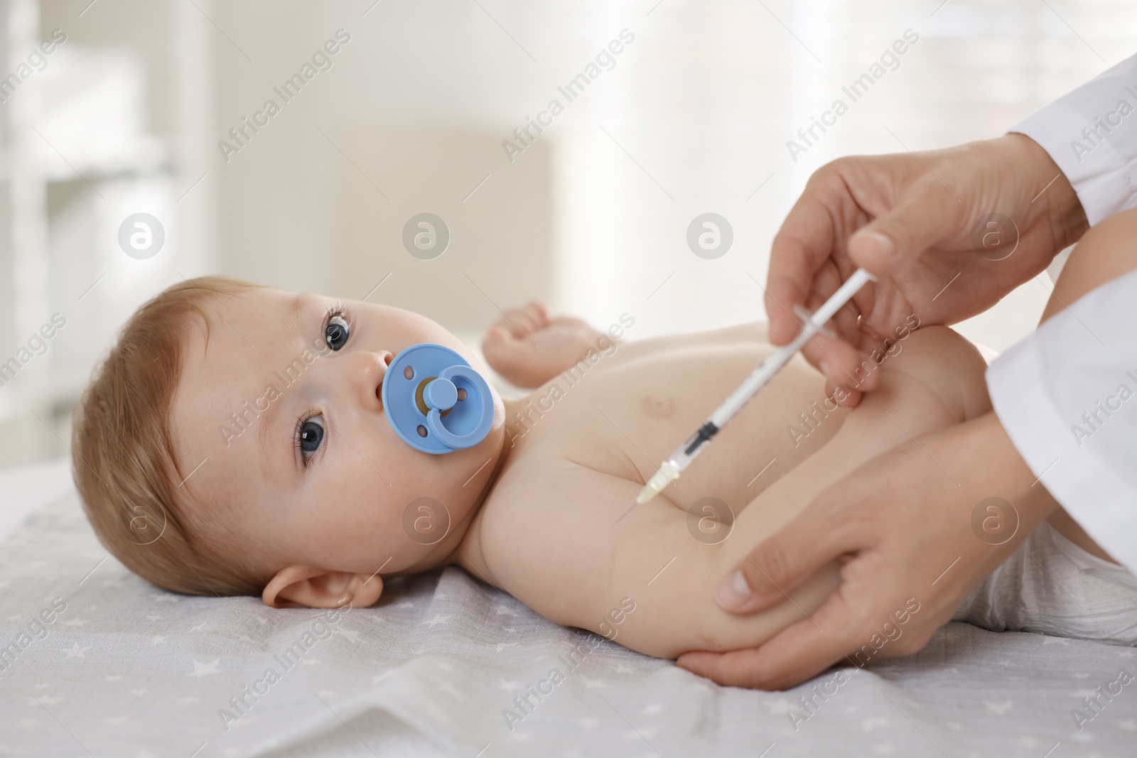 Photo of Pediatrician giving injection to cute baby in clinic, closeup