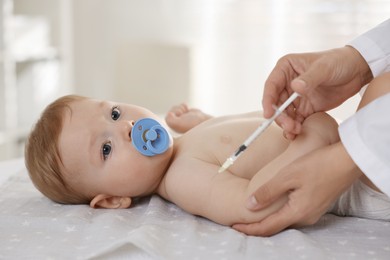 Photo of Pediatrician giving injection to cute baby in clinic, closeup