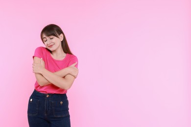 Photo of Young woman hugging himself on pink background, space for text