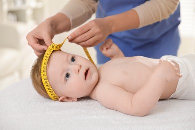 Photo of Pediatrician measuring little baby's head in clinic, closeup