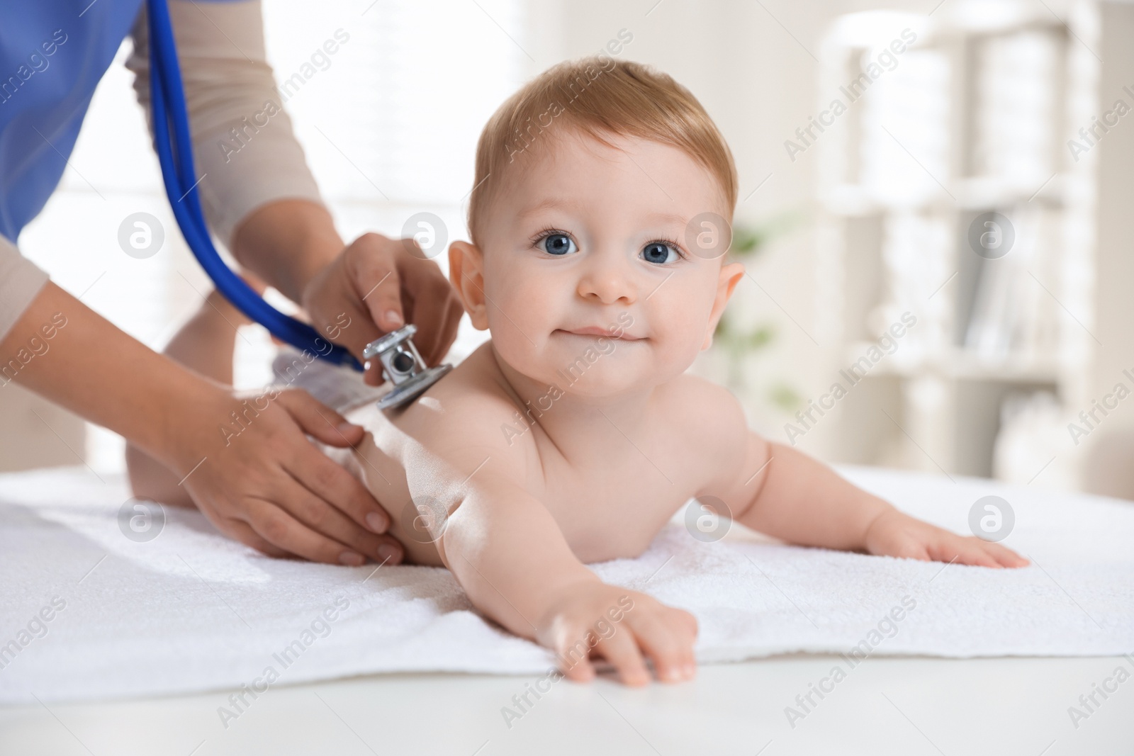 Photo of Pediatrician examining little child with stethoscope in clinic, closeup. Checking baby's health