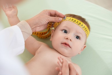 Photo of Pediatrician measuring little baby's head in clinic, closeup