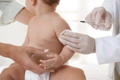 Photo of Pediatrician vaccinating little baby in clinic, closeup