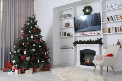 Beautifully decorated Christmas tree near fireplace in room. Festive interior design