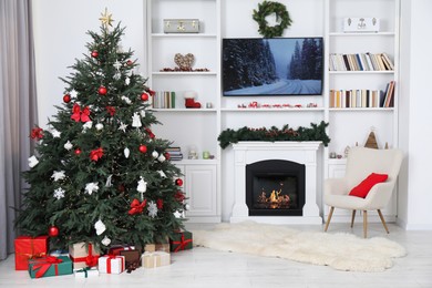 Photo of Beautifully decorated Christmas tree near fireplace in room. Festive interior design