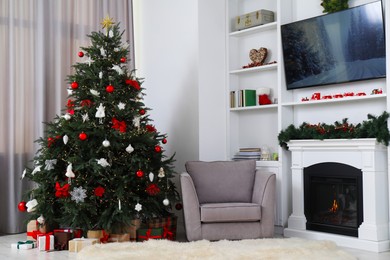 Beautifully decorated Christmas tree near fireplace in room. Festive interior design