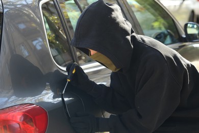 Photo of Thief with screwdriver opening fuel cap. Car hijacking