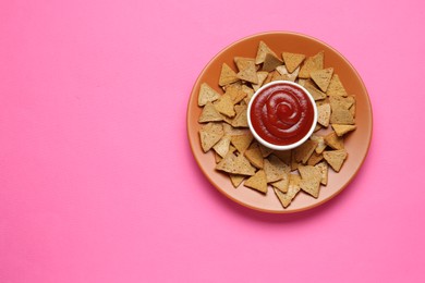 Photo of Ketchup in bowl and pieces of dry bread on pink background, top view. Space for text