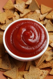 Photo of Ketchup in bowl and pieces of dry bread on plate, closeup