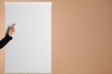 Photo of Woman near flip chart on pale brown background, closeup. Mockup for design