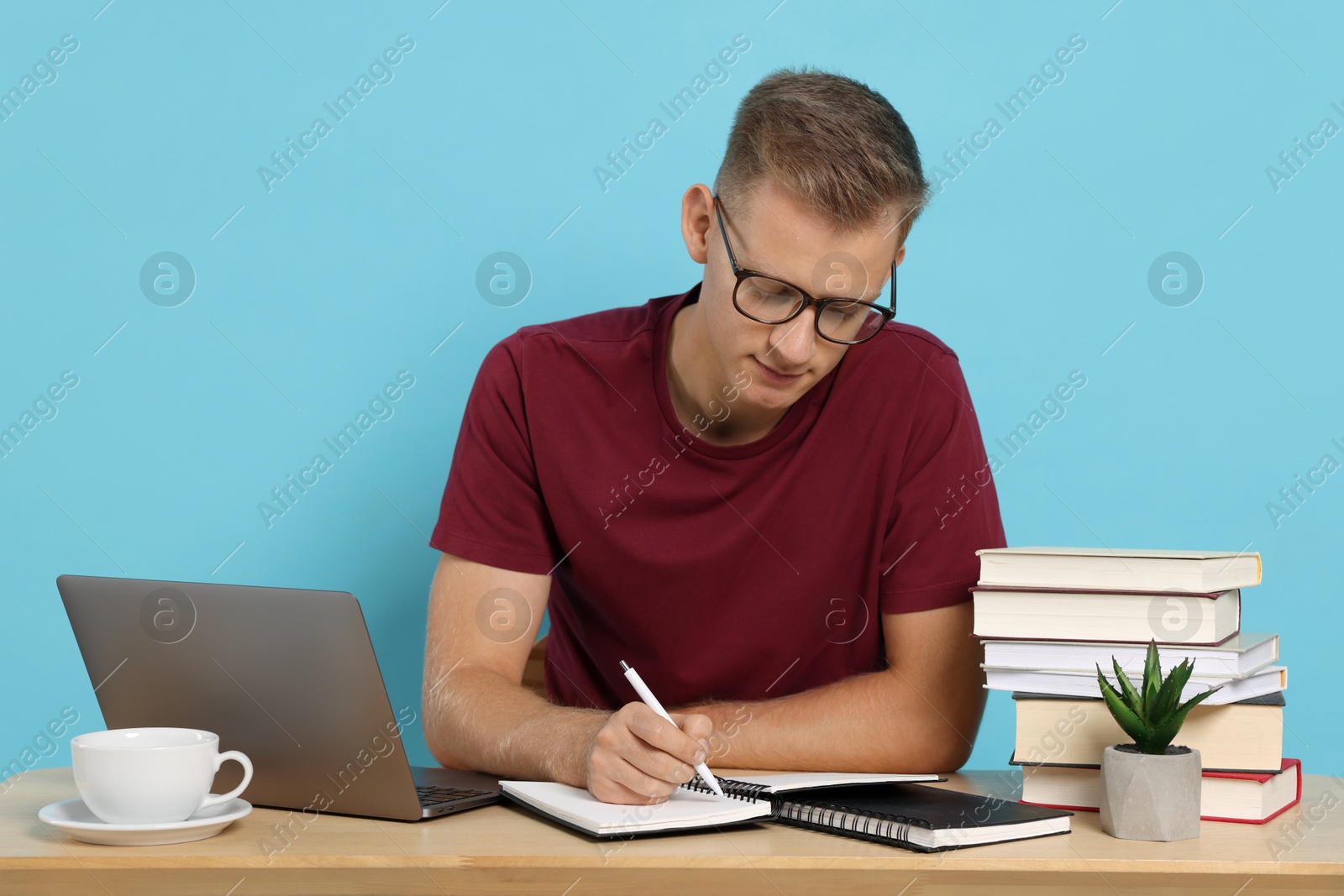 Photo of Student preparing for exam at table against light blue background