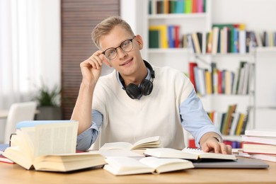 Photo of Preparing for exam. Student with books at table indoors