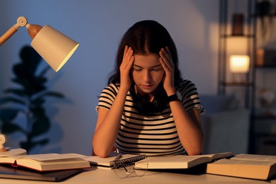 Photo of Preparing for exam. Tired student with books at table indoors