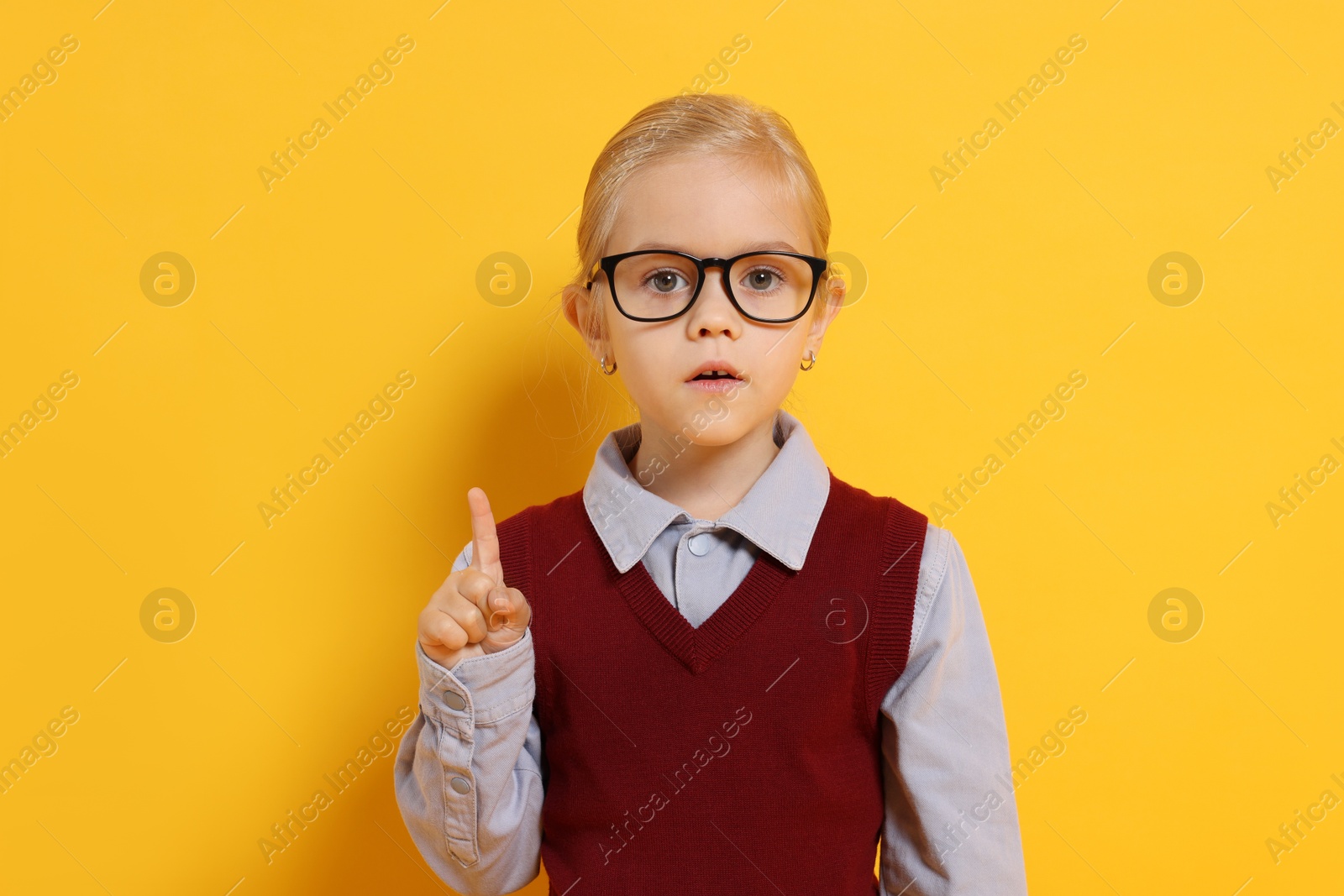 Photo of Little girl with glasses on orange background. Dreaming of future profession