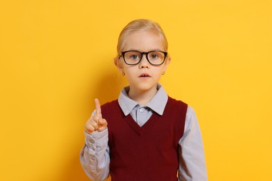 Photo of Little girl with glasses on orange background. Dreaming of future profession