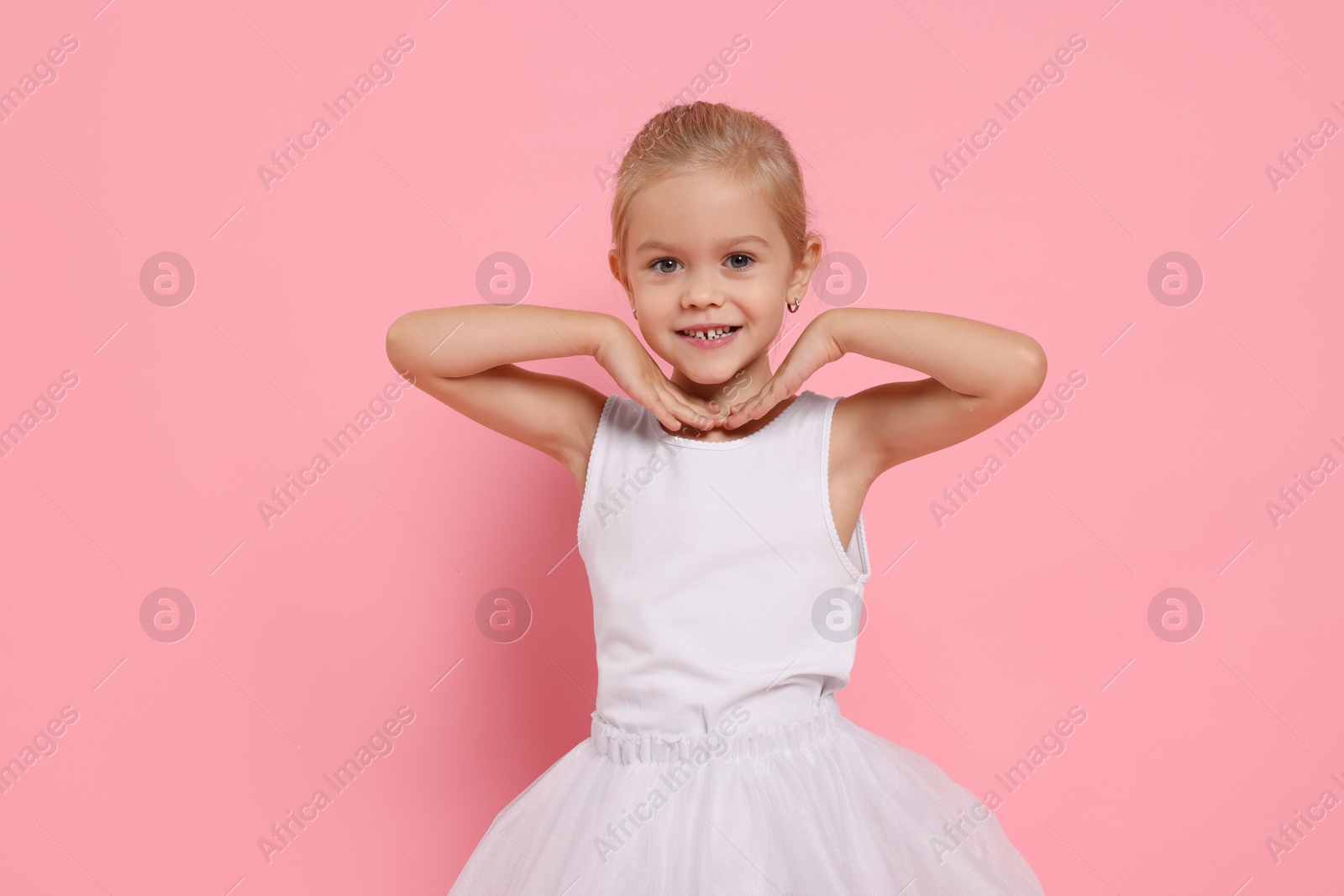 Photo of Little girl pretending to be ballerina on pink background. Dreaming of future profession