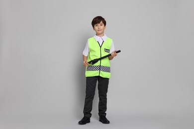 Photo of Boy pretending to be policeman on light grey background. Dreaming of future profession