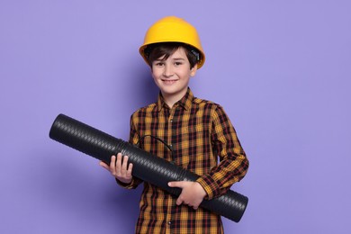 Photo of Boy with blueprint tube pretending to be architect on violet background. Dreaming of future profession