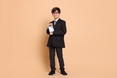 Photo of Boy with calculator pretending to be accountant on beige background. Dreaming of future profession