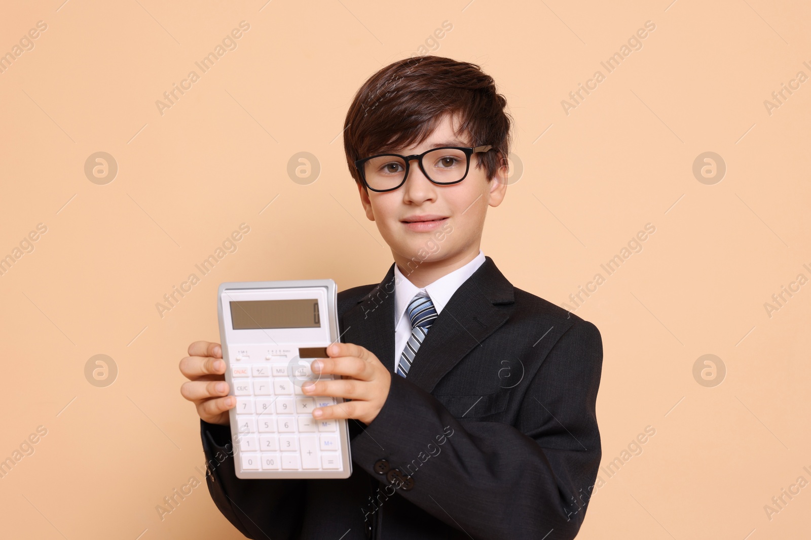 Photo of Boy with calculator pretending to be accountant on beige background. Dreaming of future profession