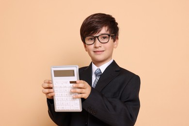 Photo of Boy with calculator pretending to be accountant on beige background. Dreaming of future profession