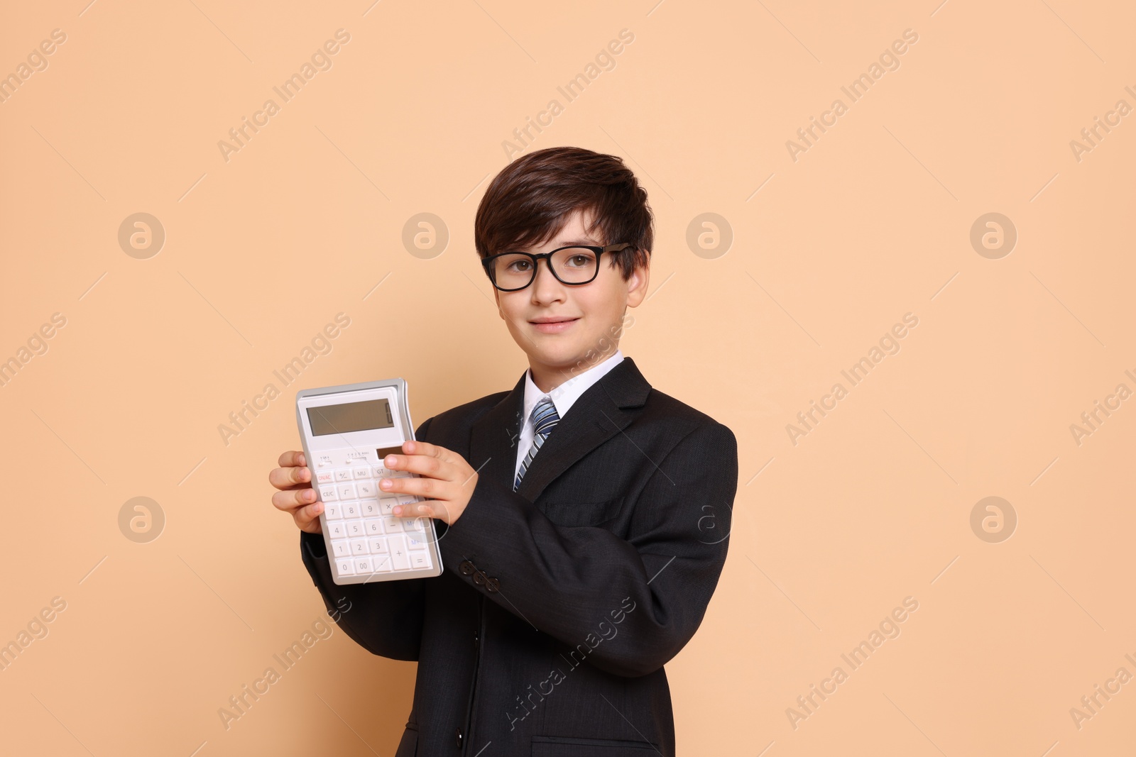 Photo of Boy with calculator pretending to be accountant on beige background. Dreaming of future profession