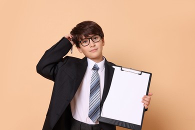 Photo of Boy with clipboard pretending to be accountant on beige background. Dreaming of future profession