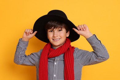 Photo of Boy with hat and scarf on orange background. Dreaming of future profession