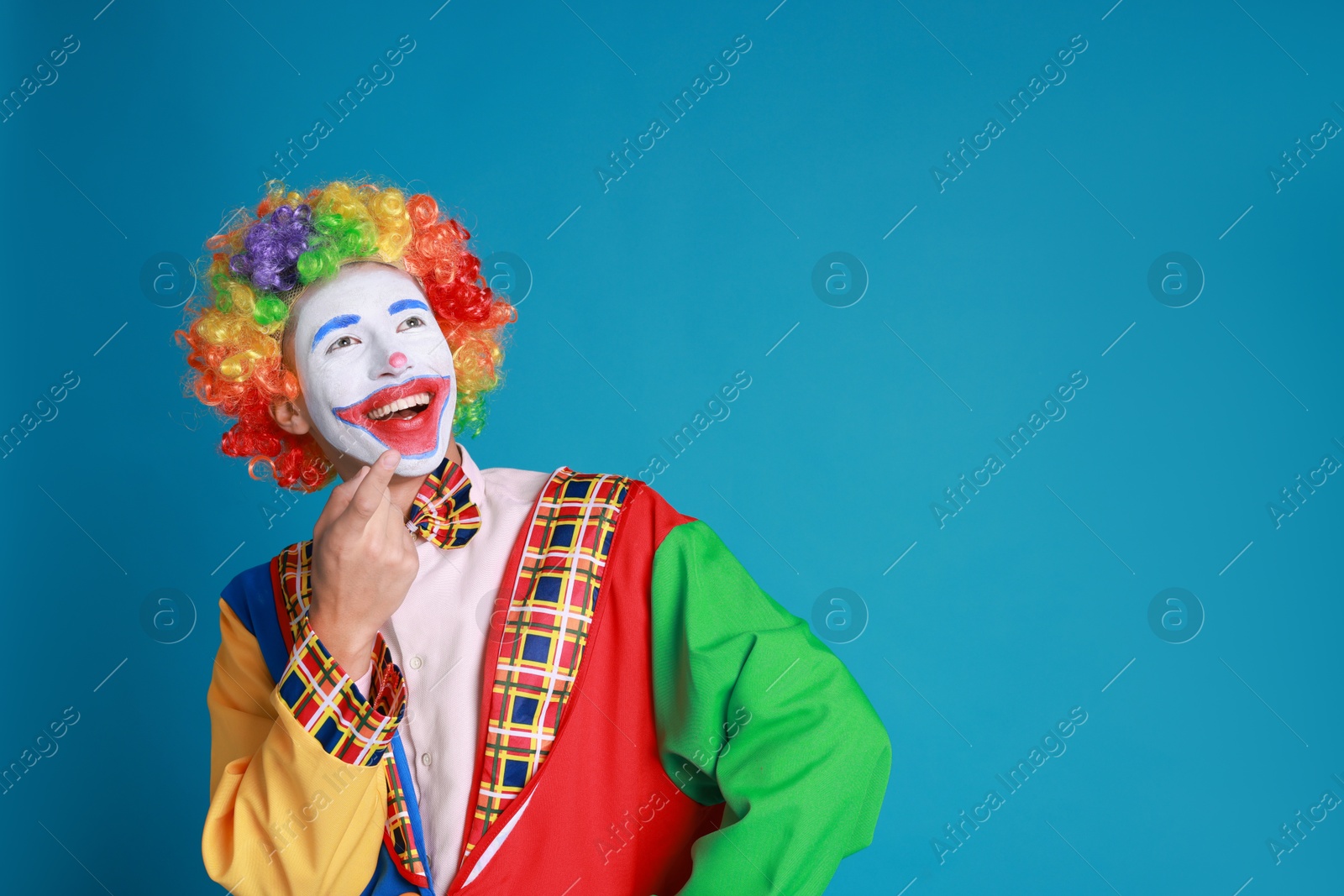 Photo of Portrait of happy clown on blue background, space for text