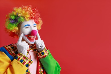 Photo of Portrait of happy clown on red background, space for text