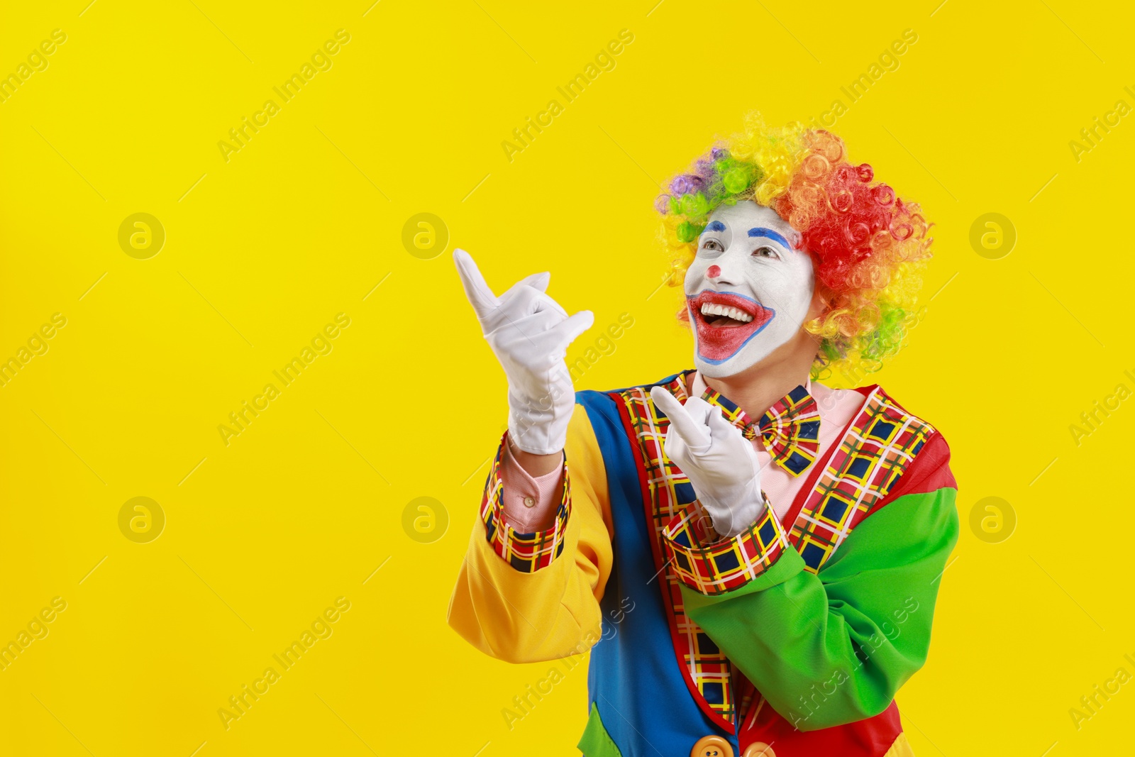 Photo of Portrait of happy clown on yellow background, space for text