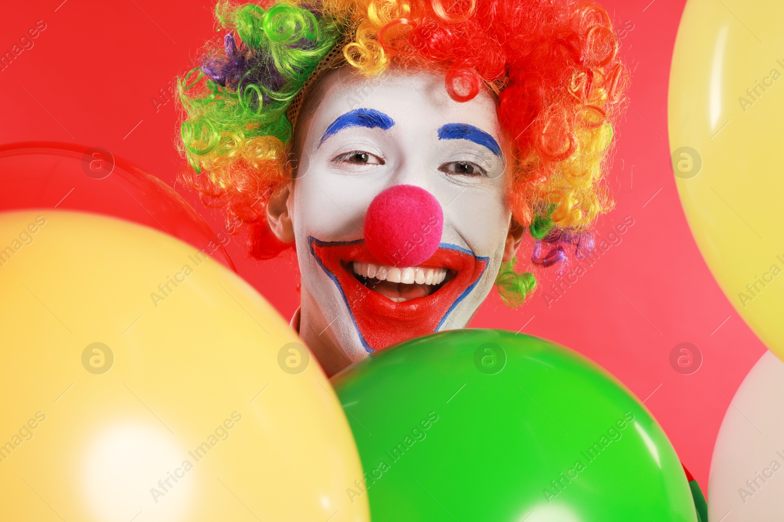 Photo of Happy clown with colorful balloons on red background