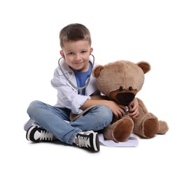 Photo of Little boy with stethoscope and toy pretending to be doctor on white background. Dreaming of future profession