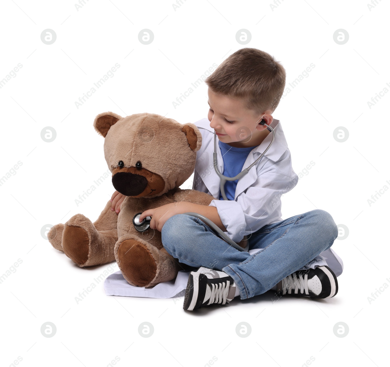 Photo of Little boy with stethoscope and toy pretending to be doctor on white background. Dreaming of future profession