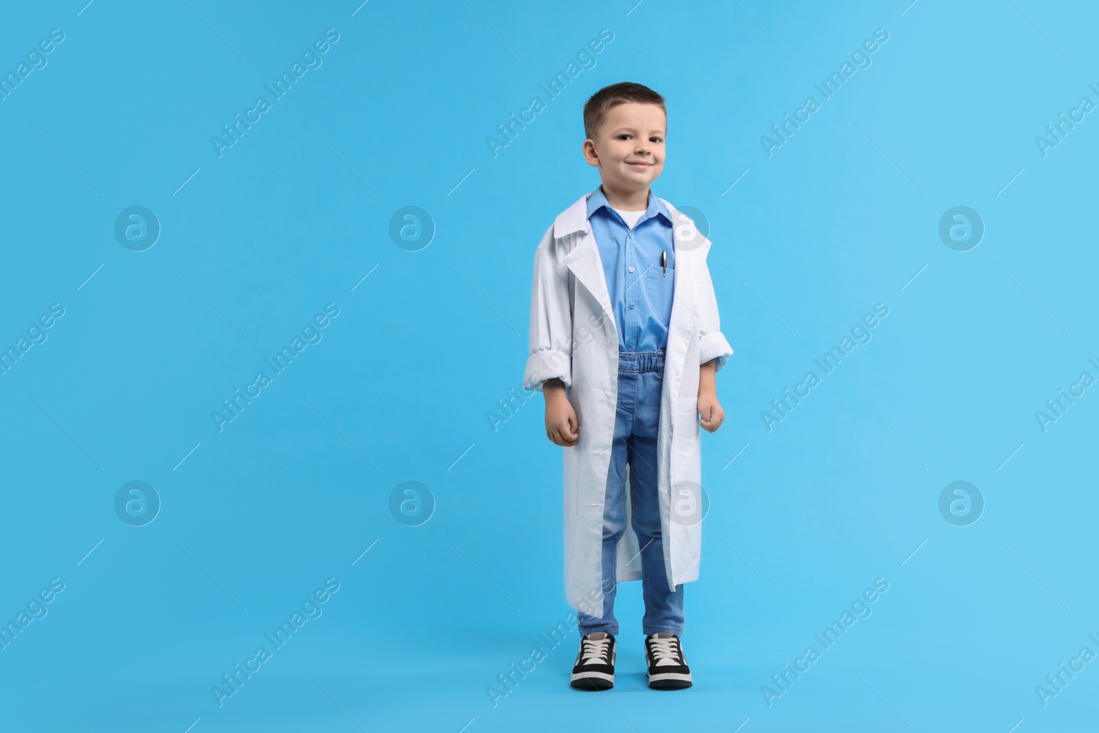 Photo of Little boy pretending to be doctor on light blue background. Dreaming of future profession