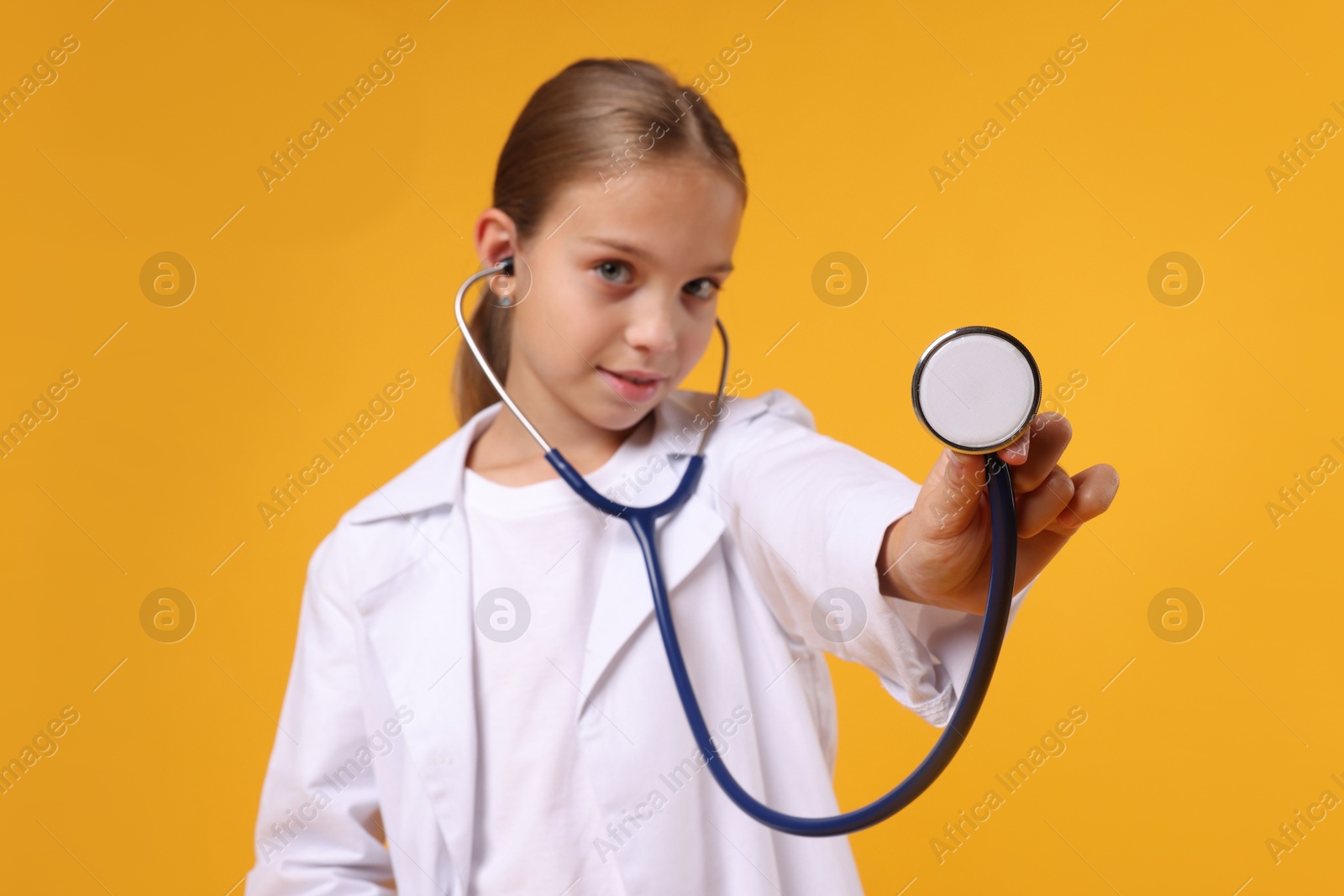 Photo of Girl with stethoscope pretending to be doctor on yellow background. Dreaming of future profession