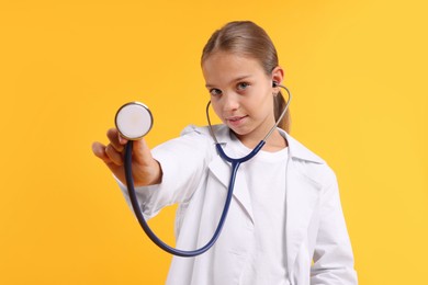 Photo of Girl with stethoscope pretending to be doctor on yellow background. Dreaming of future profession