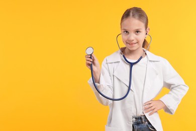 Photo of Girl with stethoscope pretending to be doctor on yellow background, space for text. Dreaming of future profession